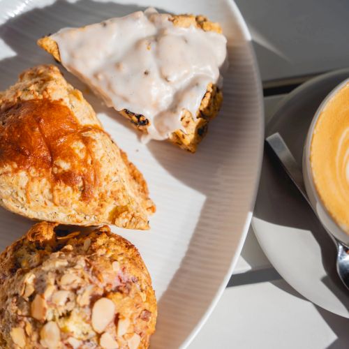 A plate of pastries with white icing and a latte with latte art beside it.