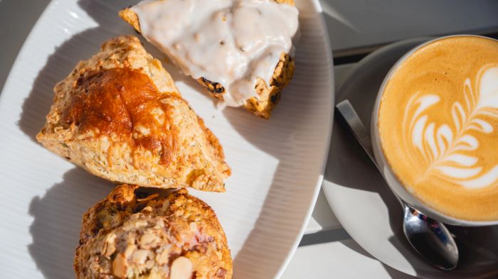 A plate with cheesy pastries and a cup of latte with latte-art foam&mdash;perfect brunch bites in the sun.